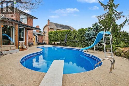 Freeform inground pool with concrete surround, diving board, and integrated slide - 2324 Homer Drive, Burlington, ON - Outdoor With In Ground Pool