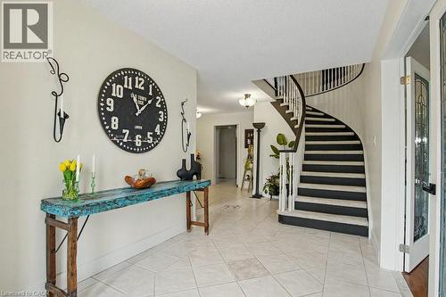 Foyer featuring a curved staircase with dark treads and white risers, white balusters, and a dark wood-finish handrail - 2324 Homer Drive, Burlington, ON - Indoor Photo Showing Living Room