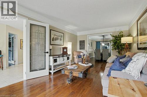 Living area featuring wood-finish flooring, crown molding, and a decorative frosted glass door - 2324 Homer Drive, Burlington, ON - Indoor Photo Showing Living Room