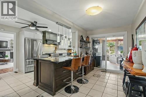 Spacious kitchen featuring an island with seating, stainless steel appliances, tile flooring, and a sliding glass door to an outdoor area - 2324 Homer Drive, Burlington, ON - Outdoor With Deck Patio Veranda