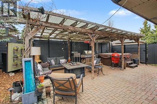 Expansive paver patio featuring a hot tub, a built-in pergola with a clear corrugated roof, and perimeter fencing - 2324 Homer Drive, Burlington, ON - Outdoor With In Ground Pool