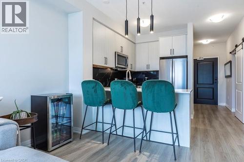 Modern kitchen with light-finish cabinetry, stainless steel appliances, and a dark stone backsplash - 120 Springvalley Crescent Unit# 208, Hamilton, ON - Indoor Photo Showing Other Room