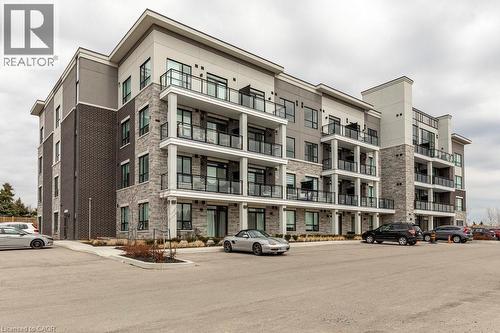 Contemporary multi-story building featuring a blend of dark brick, light stone veneer, and light-toned siding - 120 Springvalley Crescent Unit# 208, Hamilton, ON - Outdoor With Balcony With Facade