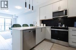 Modern kitchen featuring white cabinetry, light-toned countertops, and a striking dark backsplash - 