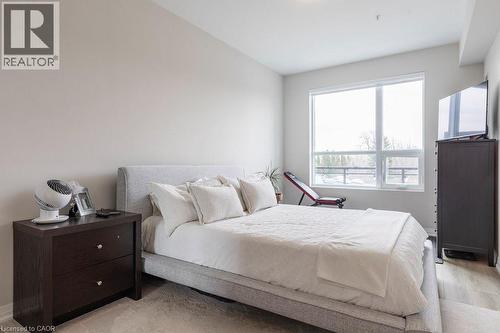 Bright bedroom featuring a large window, neutral wall tones, and light wood-finish flooring - 120 Springvalley Crescent Unit# 208, Hamilton, ON - Indoor Photo Showing Bedroom