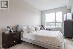 Bright bedroom featuring a large window, neutral wall tones, and light wood-finish flooring - 