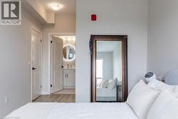 Bathroom entry featuring a vanity with a circular back-lit mirror, a wall-mounted faucet, and light wood-finish flooring - 