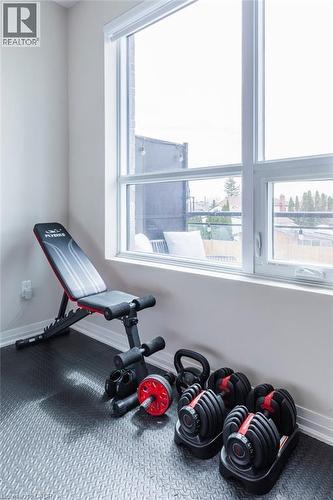 Generous natural light from large windows illuminates a durable, textured flooring - 120 Springvalley Crescent Unit# 208, Hamilton, ON - Indoor Photo Showing Gym Room