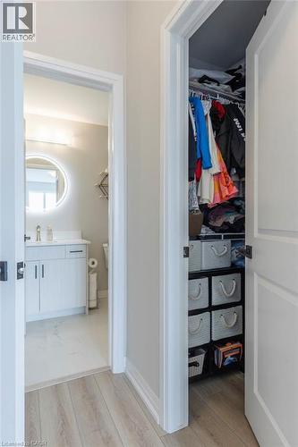 Hallway with wood-finish flooring featuring a full bathroom and a closet - 120 Springvalley Crescent Unit# 208, Hamilton, ON - Indoor