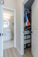 Hallway with wood-finish flooring featuring a full bathroom and a closet - 