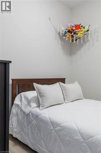 Neutral wall color with wood-finish flooring and a wood headboard - 120 Springvalley Crescent Unit# 208, Hamilton, ON - Indoor Photo Showing Bedroom
