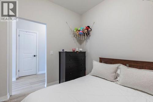 Bedroom featuring neutral wall colors, light wood-finish flooring, and a two-panel interior door with dark hardware - 120 Springvalley Crescent Unit# 208, Hamilton, ON - Indoor Photo Showing Bedroom