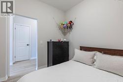 Bedroom featuring neutral wall colors, light wood-finish flooring, and a two-panel interior door with dark hardware - 