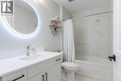 Contemporary bathroom featuring a light wood-finish vanity with black hardware, a pristine white countertop, and an integrated rectangular sink - 