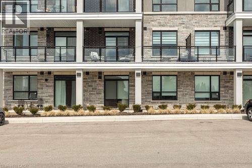 Contemporary multi-story building featuring stone veneer and dark brick facade accents - 120 Springvalley Crescent Unit# 208, Hamilton, ON - Outdoor With Balcony With Facade