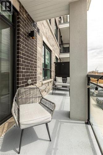 Private balcony with a concrete floor, featuring a glass panel railing and a dark brick exterior wall - 120 Springvalley Crescent Unit# 208, Hamilton, ON - Outdoor With Balcony With Exterior
