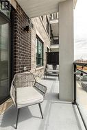 Private balcony with a concrete floor, featuring a glass panel railing and a dark brick exterior wall - 