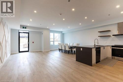 Open-concept living space featuring wood-finish flooring, recessed lighting, and a kitchen island with integrated sink - 120 Springvalley Crescent Unit# 208, Hamilton, ON - Indoor Photo Showing Kitchen With Upgraded Kitchen