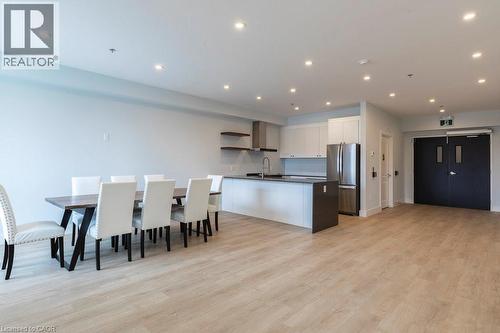 Open-concept living space featuring wood-finish flooring, recessed lighting, and a contemporary kitchen with white cabinetry, stainless steel appliances, and a central island with a sink - 120 Springvalley Crescent Unit# 208, Hamilton, ON - Indoor