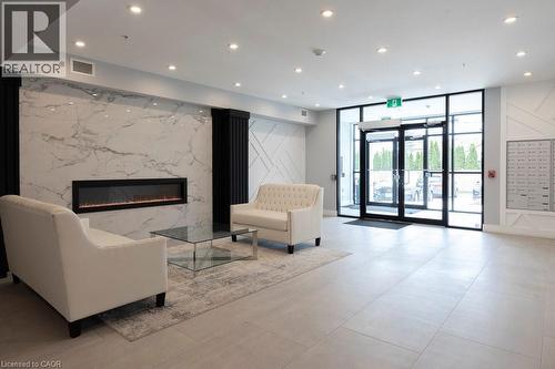 Lobby featuring a fireplace with a large-format marble-effect surround, light tile flooring, and recessed ceiling lighting - 120 Springvalley Crescent Unit# 208, Hamilton, ON - Indoor Photo Showing Other Room With Fireplace