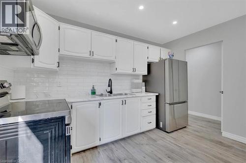 Kitchen featuring white cabinetry, subway tile backsplash, stainless steel appliances, marble-finish countertops, and wood-finish flooring - 168 Silver Aspen Crescent, Kitchener, ON - Indoor Photo Showing Kitchen