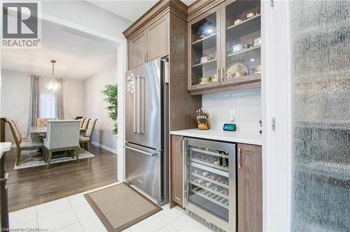Bar area featuring wine cooler, fridge, glass insert cabinets, light tile patterned floors, and decorative light fixtures - 49 Scots Pine Trail, Kitchener, ON - Indoor