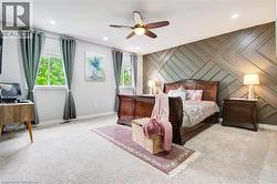 Bedroom featuring an accent wall, a ceiling fan, cozy bedroom carpet, and big windows - 