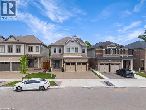 View of front of house featuring a residential view, exposed concrete driveway, an attached garage, and brick siding - 49 Scots Pine Trail, Kitchener, ON - Outdoor With Facade