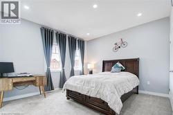Bedroom with light colored carpet, an office area, and recessed lighting - 