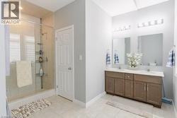 Full bathroom featuring double vanity, light tile patterned floors, and a stall shower - 