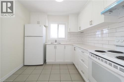 Kitchen with white appliances, white cabinets, ventilation hood, and light countertops - 24 Austin Drive, Waterloo, ON - Indoor Photo Showing Kitchen