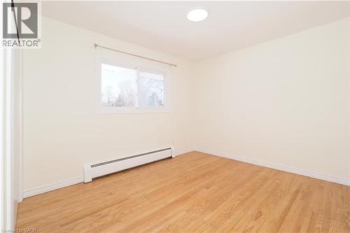 Empty room featuring a baseboard radiator and light wood-type flooring - 24 Austin Drive, Waterloo, ON - Indoor Photo Showing Other Room