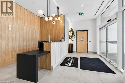 Modern reception area featuring wood-finish wall paneling, a white and black reception desk, and sleek contemporary lighting - 500 Plains Road E Unit# 207, Burlington, ON - Indoor Photo Showing Other Room