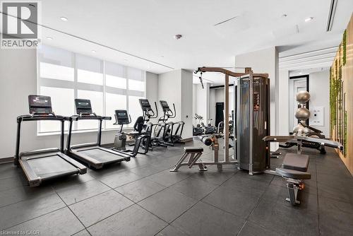 Spacious fitness center featuring various cardio machines, weight training equipment, resilient flooring, and ample natural light through large windows with roller shades - 500 Plains Road E Unit# 207, Burlington, ON - Indoor Photo Showing Gym Room