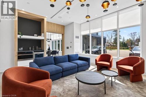 Spacious common area featuring large windows with roller shades, a built-in wet bar with wood-finish cabinetry, recessed lighting, and modern ceiling fixtures - 500 Plains Road E Unit# 207, Burlington, ON - Indoor Photo Showing Living Room
