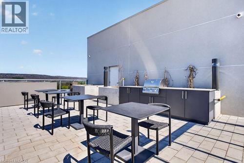 Expansive rooftop patio featuring paver flooring, a built-in stainless steel grill, integrated cabinetry, and a concrete countertop - 500 Plains Road E Unit# 207, Burlington, ON - Outdoor With Exterior