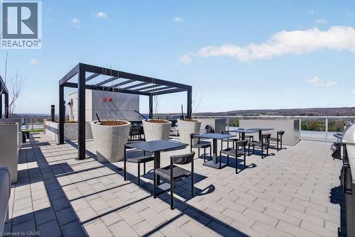 Rooftop patio with paver flooring, modern pergola, built-in planters, and a stainless steel outdoor grill - 500 Plains Road E Unit# 207, Burlington, ON - Outdoor