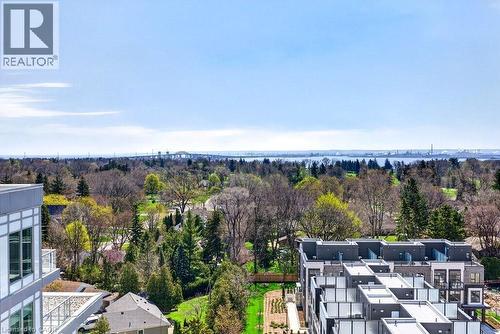 Elevated perspective showcasing a distant body of water with a bridge, surrounded by extensive tree coverage and residential structures - 500 Plains Road E Unit# 207, Burlington, ON - Outdoor With View