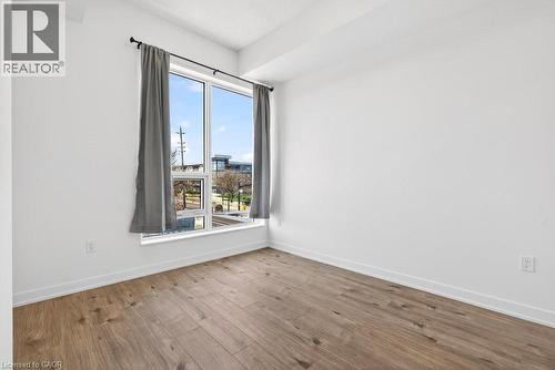 Room with wood-finish flooring, white walls, and a large window - 500 Plains Road E Unit# 207, Burlington, ON - Indoor Photo Showing Other Room