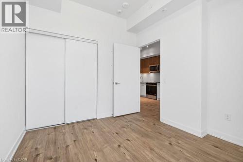 Room featuring wood-finish flooring, white walls, and a built-in closet with sliding doors - 500 Plains Road E Unit# 207, Burlington, ON - Indoor Photo Showing Other Room