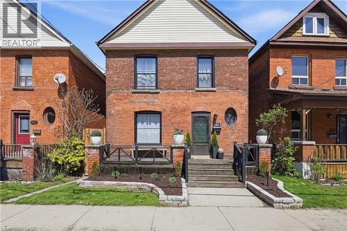 Brick facade residential property featuring a covered front porch with dark wood railings - 361 Cumberland Avenue, Hamilton, ON - Outdoor With Deck Patio Veranda With Exterior