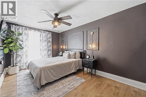 Bedroom featuring wood-finish flooring, a ceiling fan with integrated lighting, and a dark accent wall - 361 Cumberland Avenue, Hamilton, ON - Indoor Photo Showing Bedroom