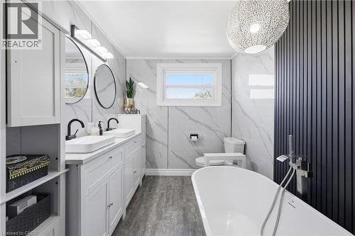 Bathroom featuring a freestanding white bathtub, a dual vanity with white rectangular vessel sinks, and black hardware - 361 Cumberland Avenue, Hamilton, ON - Indoor Photo Showing Bathroom