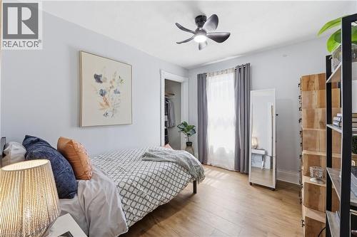 Bedroom featuring wood-finish flooring, a ceiling fan with integrated lighting, and a window with drapes - 361 Cumberland Avenue, Hamilton, ON - Indoor Photo Showing Bedroom
