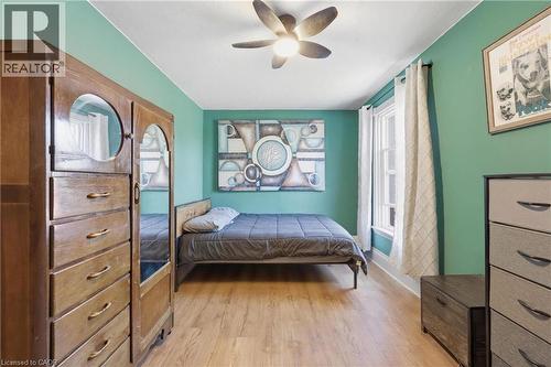 Bedroom featuring wood-finish flooring, a ceiling fan with integrated lighting, and a single window with white trim - 361 Cumberland Avenue, Hamilton, ON - Indoor Photo Showing Bedroom