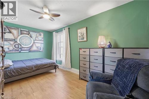 Bright interior space featuring green walls, wood-finish flooring, a ceiling fan with integrated lighting, and a single window with white trim - 361 Cumberland Avenue, Hamilton, ON - Indoor Photo Showing Bedroom