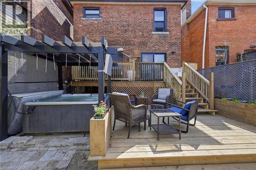 Expansive backyard featuring a multi-level wood deck, a patio with pavers, a built-in hot tub under a pergola, and a privacy fence - 361 Cumberland Avenue, Hamilton, ON - Outdoor With Deck Patio Veranda With Exterior