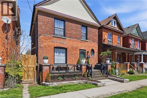 Brick facade residence featuring a front porch with dark railings and steps - 361 Cumberland Avenue, Hamilton, ON - Outdoor With Deck Patio Veranda