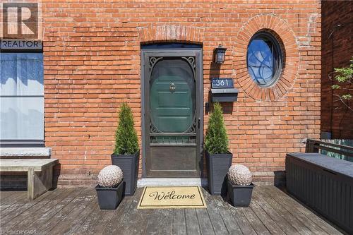 Brick facade featuring a recessed entry with an ornate screen door and an oval window - 361 Cumberland Avenue, Hamilton, ON - Outdoor With Exterior