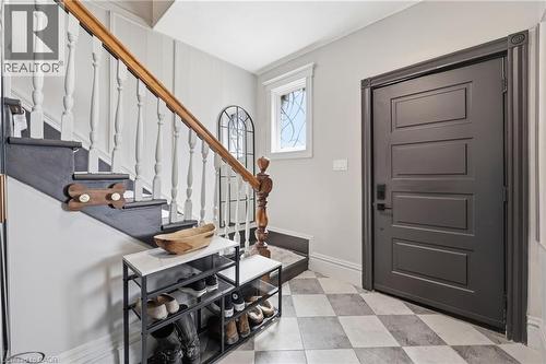 Entryway featuring a patterned tile floor, dark paneled door, traditional wooden staircase with white balusters, and transom window - 361 Cumberland Avenue, Hamilton, ON - Indoor Photo Showing Other Room